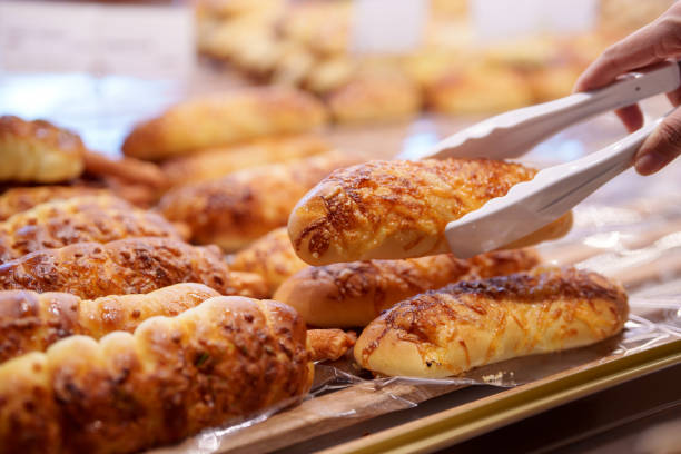 Woman selecting fresh bread buns from bakery display