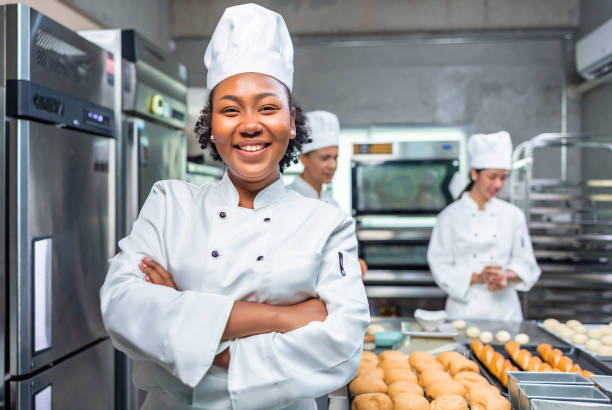 African American woman bakers looking at camera chef baker in a chef dress and hat cooking
